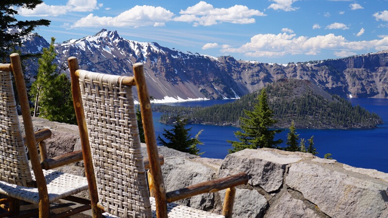 A view of Crater Lake with island in middle of water seen from the back of wicker wood rattan rocking chairs